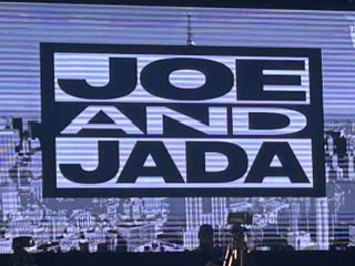 Display screen featuring the text 'JOE AND JADA' over a city skyline backdrop.